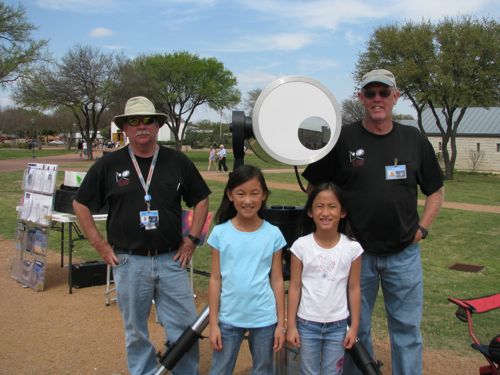 Cherry and Coco stand with astronomy enthusiasts and their telescope.